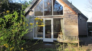 Ein kleines, eingeschossiges Haus mit einem großen Glasbalkon und einer Holzveranda.