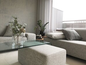 A modern living room with a glass coffee table, two sofas, and a potted plant. - Roost Lapinrinne (Helsinki)