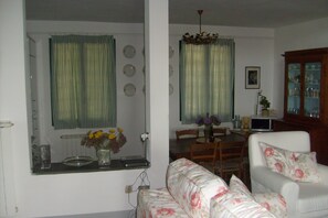 A living room with a sofa, a dining table, and a cabinet.