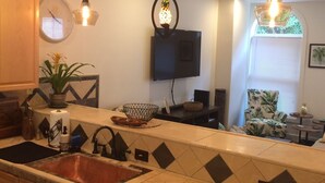 A kitchen with a central island, a dishwasher, a sink, and a television mounted on the wall.