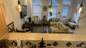 A spacious living area with a large window, a kitchen with a copper sink, and a staircase leading to another level.