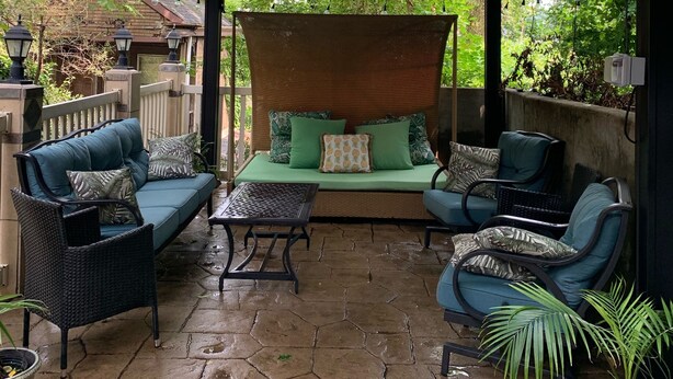 A covered outdoor seating area with a gazebo, wicker furniture, and potted plants.