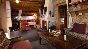 Een gezellige woonkamer met een open haard, een bank, een bijzettafeltje met brood en een boekenkast.