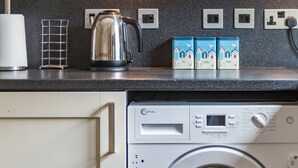 A kitchen with a kettle, tea, coffee, and sugar boxes, a washing machine, and a power outlet. - Modern holiday home in Walmer, Deal with parking (Deal)