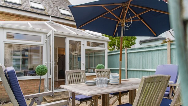 A conservatory with a table and chairs, a blue umbrella, and a small tree. - Modern holiday home in Walmer, Deal with parking (Deal)