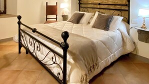 A bedroom with a stone arch wall, a bed with a headboard, a nightstand with a lamp, and a wooden ceiling. - Legnaia countryside luxury property, shared pool, ideal base to discover Tuscany (Siena)