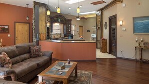 A spacious living room with a leather sofa, a wooden coffee table, and a kitchen area with a bar.