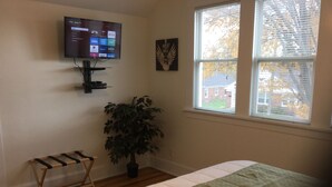 A bedroom with a bed, a TV mounted on the wall, a potted plant, and a window with blinds. - Relaxing! Professionally Cleaned, Self Check In - Sleeps 12 (Racine)