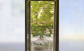 Relax in a serene outdoor space with a view of lush greenery, surrounded by a beautifully designed fence and comfortable seating for two.
