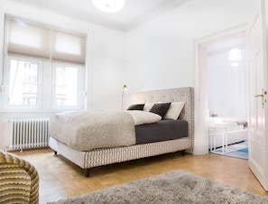 Relax in this serene bedroom with a large bed, wooden floor, and a stylish bedside table.