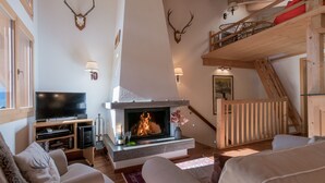 A cozy living room with a fireplace, a TV, and a staircase leading to an upper level.