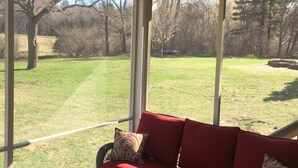 A covered patio with a red sofa, a glass table, and a ceiling fan.