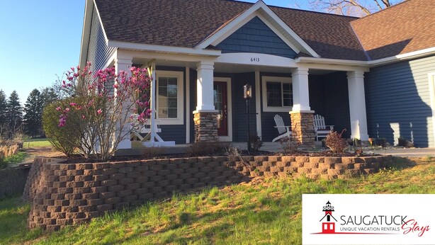 A two-story house with a stone foundation, a front porch with white columns, and a number '6413' on the house.