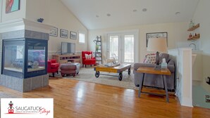 A spacious living room with a fireplace, red and grey sofas, a coffee table, and a television.