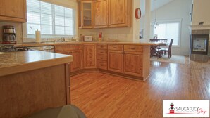 A kitchen with wooden cabinets, a stove, and a dining area with a table and chairs.