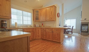 Una cocina con armarios de madera, una estufa y un comedor con mesa y sillas.
