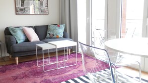A living room with a grey sofa, a white coffee table, a glass dining table, and a purple rug. - Ripple - near Congress Centre & River- A/C, swimming, pool, secure parking (Lisboa)