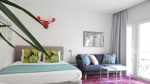 A modern bedroom with a bed, a sofa, a coffee table, and a large window. - Ripple - near Congress Centre & River- A/C, swimming, pool, secure parking (Lisboa)