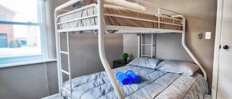 Habitación con literas, una ventana, una planta pequeña y una puerta.