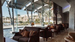A modern lounge area with a pool view, comfortable seating, and a glass-enclosed patio.