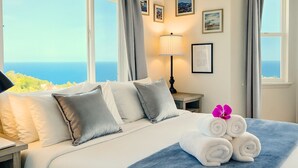 Et hotelværelse med en seng, et natbord, en lampe og havudsigt.