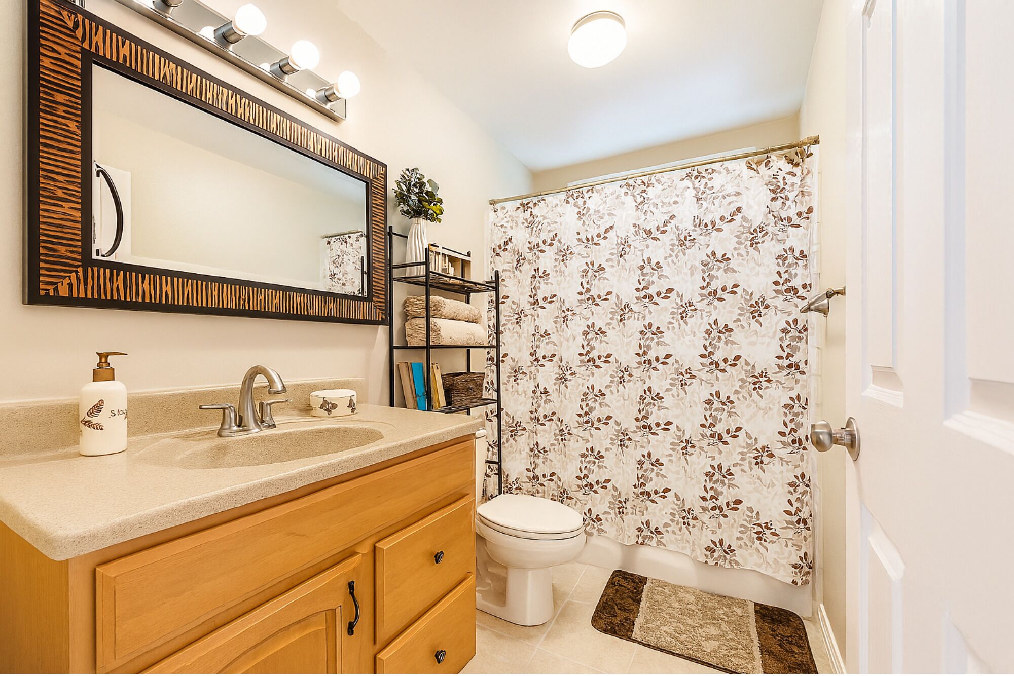A bathroom with a vanity, sink, mirror, and toilet.