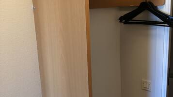 Un armario de madera con espacio para colgar y un interruptor de luz en la pared.