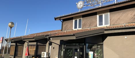 Un edificio con un letrero que dice "VARDSHUSET GLACIA" y un área de estar al aire libre cubierta con bancos.