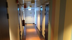 Un long couloir étroit, doté d’un plancher en bois et de portes des deux côtés.