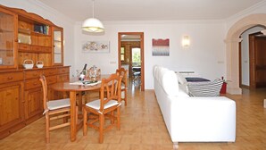 Ein Essbereich mit einem Holztisch, Stühlen, einem weißen Sofa und einem Holzschrank.