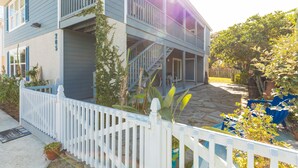 A two-story house with a white picket fence, a stone patio, and potted plants. - Beachy Getaway–Cozy, Clean & Equipped w/ All Essentials! Relax, Enjoy & Refresh! (St Augustine Beach)
