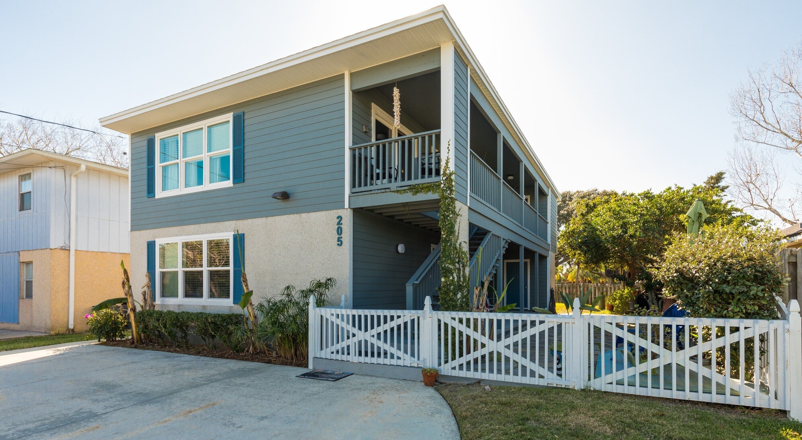 A two-story building with a balcony, a white picket fence, and a number '205' on the side.