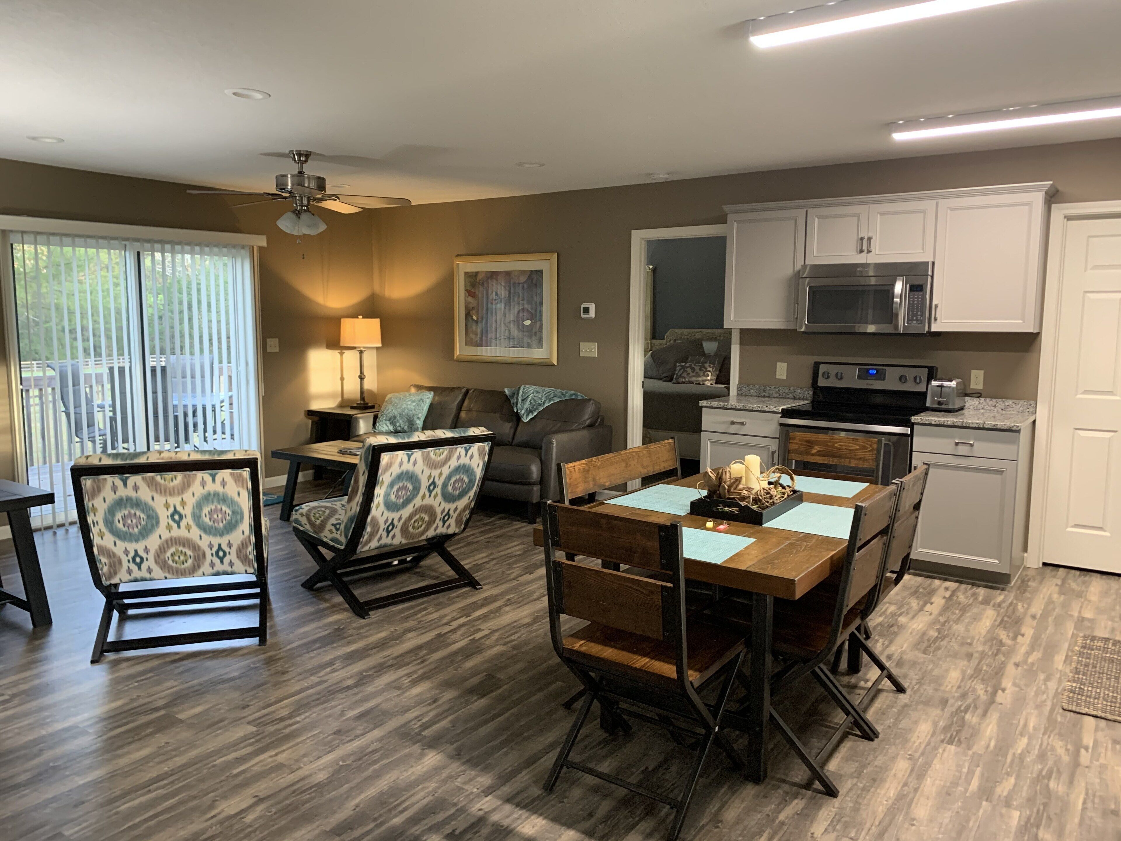 A modern kitchen with white cabinets, a microwave, and a stove. There is a dining area with a wooden table and chairs.