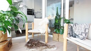A modern living room with a sofa, a chair, a fur rug, and several potted plants. - Roost Lauttasaari (Helsinki)