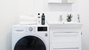 A modern bathroom with a white washing machine, a sink, and a mirror. - Roost Lauttasaari (Helsinki)