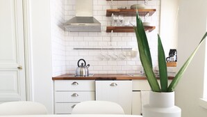 Eine moderne Küche mit weißen Schränken, einem Wasserkocher auf der Arbeitsfläche und einem Blumentopf.