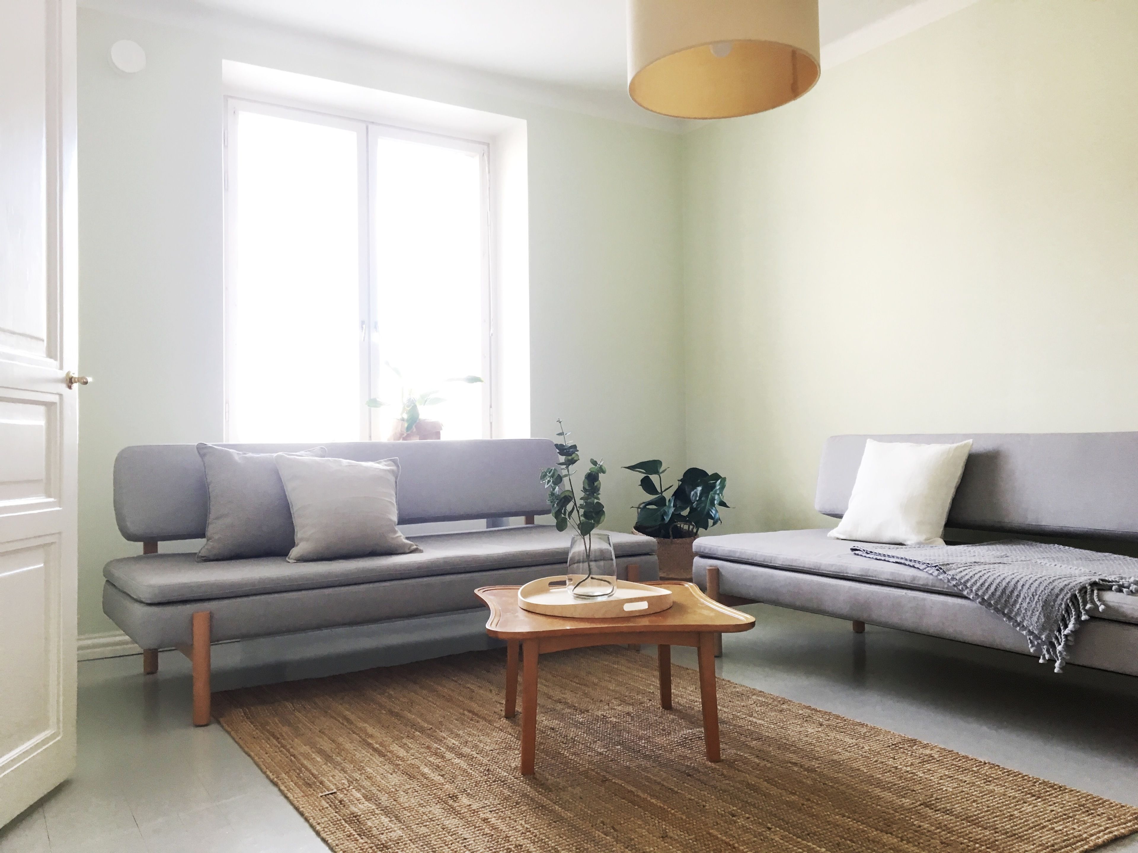 Un salon avec un canapé gris, une table basse en bois et une grande fenêtre.