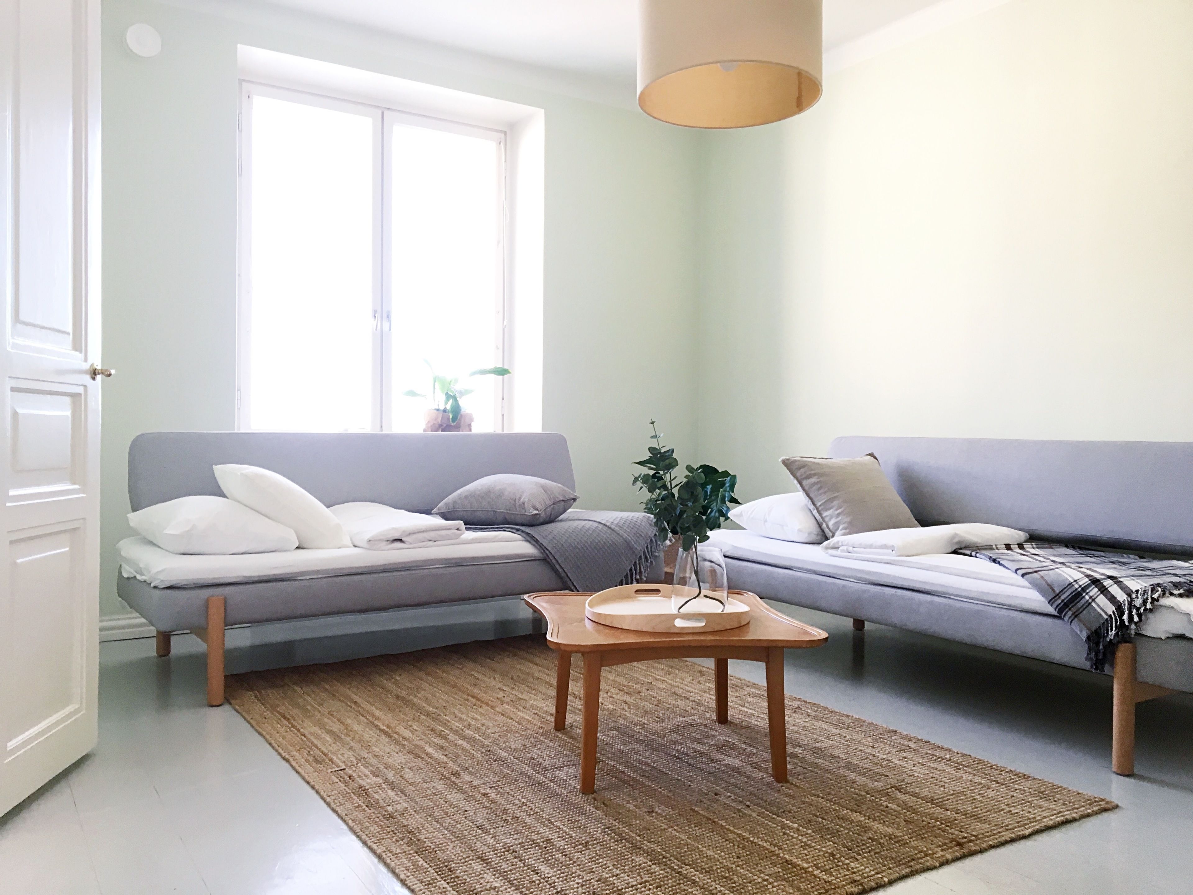A modern living room with two grey sofas, a wooden coffee table, and a large window providing natural light.