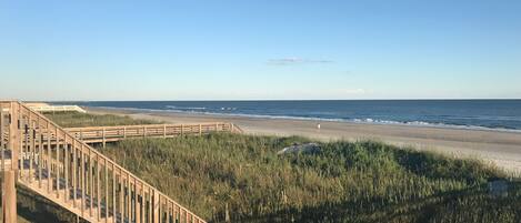 A wooden boardwalk leading to a beach with a clear view of the ocean.