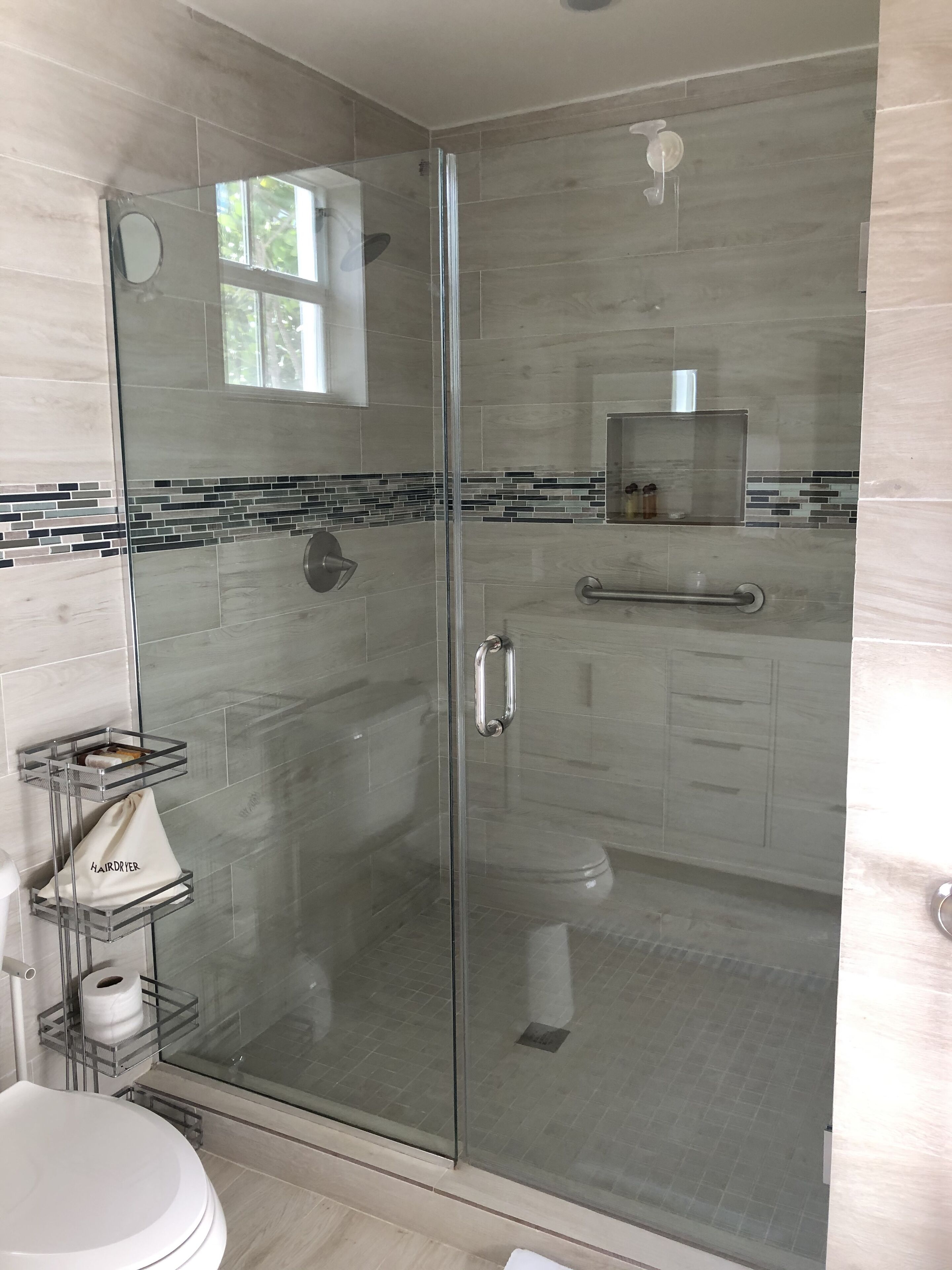 A modern bathroom with a glass-enclosed shower, a toilet, and a sink.