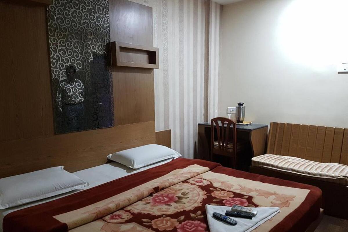Habitació d'hotel amb un llit, una taula de treball, una cadira i una finestra amb cortines.
