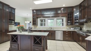 Una cocina moderna con armarios de madera oscura, una isla central y electrodomésticos integrados.