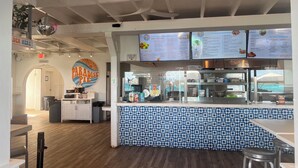 A restaurant interior with a counter, menu boards, and a 'Paradise Pie' sign.