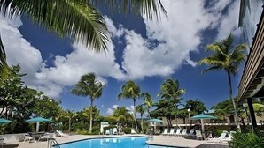 A swimming pool with lounge chairs and palm trees.