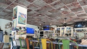 A bar with colorful chairs, a ceiling with a geometric pattern, and various artworks on the walls.