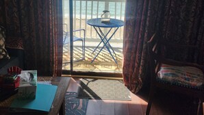 Una habitación con vistas a la playa, una mesa con un frasco de vidrio, una silla y suelo de madera.