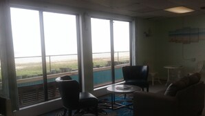 Una habitación con ventanas amplias, una mesa redonda, dos sillas, un sofá y una pequeña mesa con una silla.
