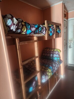 A bunk bed with a ladder, a chair with a patterned cushion, and a door with a sign. - Sands of time,VIEW 180°, PEACEFUL,360° VIDEO,WIFI, CABLE,ROKU,DVDS, FALL CHEAPER (Corpus Christi)