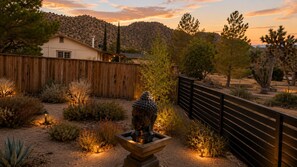 Un paysage désertique avec une clôture en bois, une maison et différentes espèces de plantes désertiques.