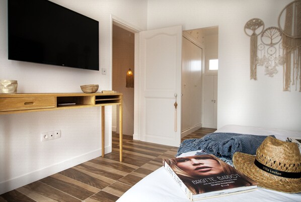 Ein Schlafzimmer mit einem Bett, einem an der Wand montierten Fernseher, einem Nachttisch mit einer Schale und einem Buch auf dem Bett.
